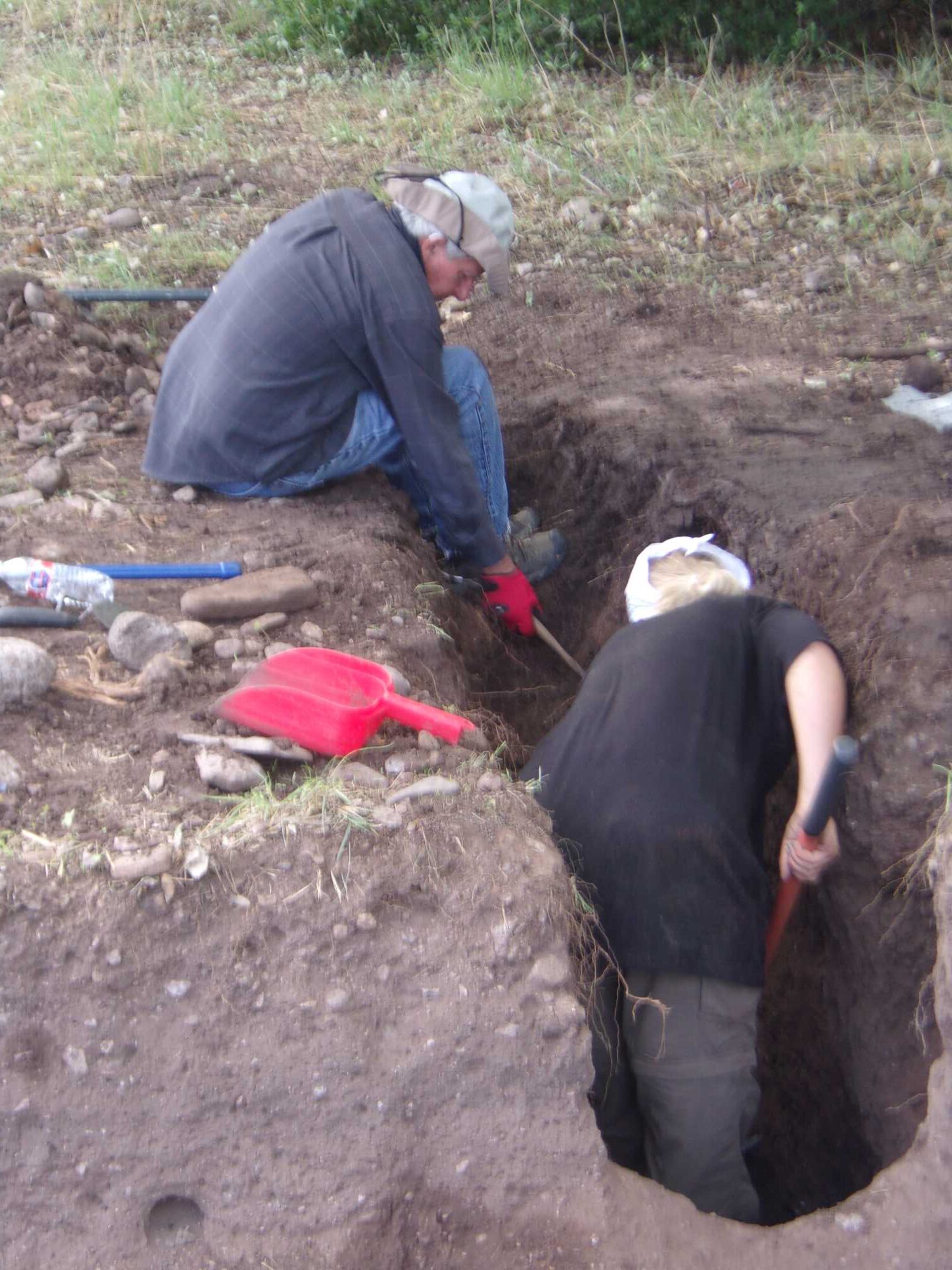 Phil Hunger using a patiche excavation tool for the first time, assisting student crew Emily Barrick.