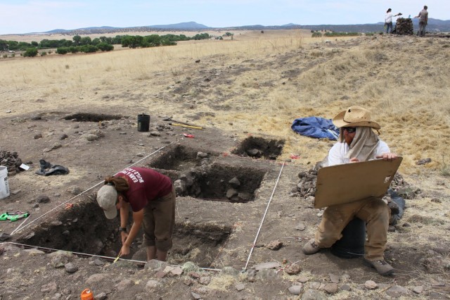 Field Supervisor Rob Jones draws a wall profile of kiva test units while a student excavates.