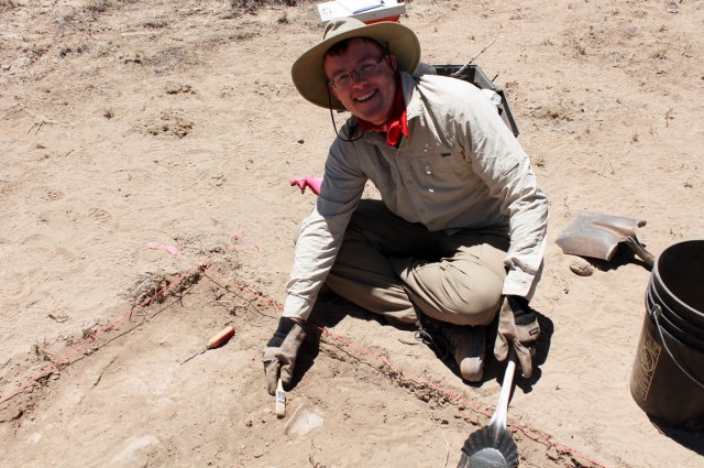 Thatcher brushes soil away from a rim sherd.