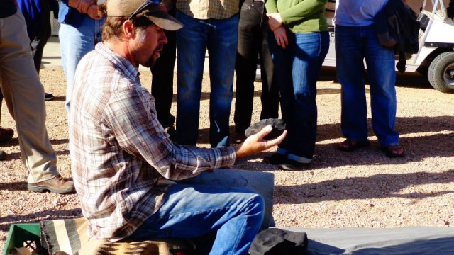 Allen holds a stone spear point that he is flaking into shape.