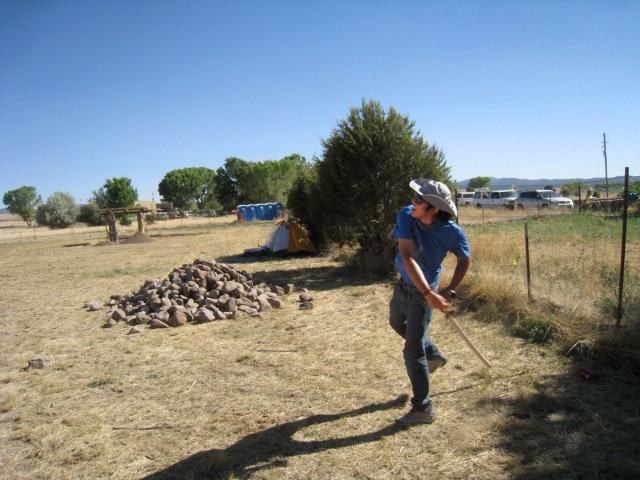 Chris throws darts near a pile of stones ready to be used in the foundation of our adobe room. Several atlatls have already been crafted in the shade of the ramada in the background. Photo by Allen Denoyer.