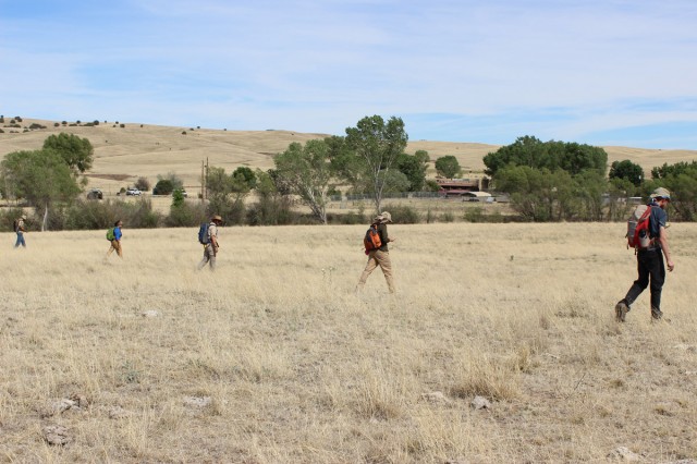 Students prepare for survey work by keeping one eye on their compass bearing, one on their spacing from their neighbors, and a third on the ground to report any artifacts they spot. Wait, how many eyes is that?