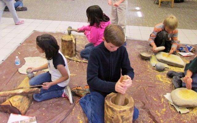 Students crowd in to try chopping and grinding activities.