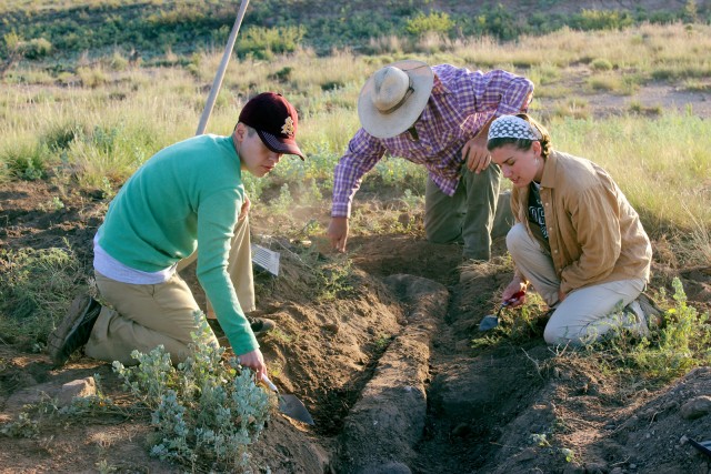 Diana, Will, and Anna excavate the top of an adobe wall.
