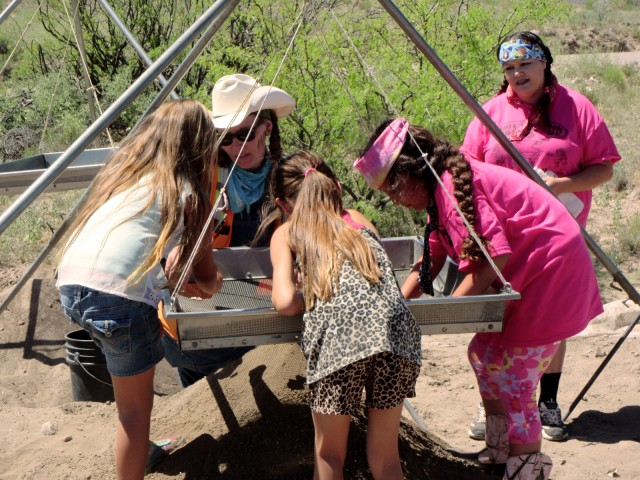 Leslie Aragon helps visiting Girl Scouts find artifacts in the screen at the Preservation Archaeology Field School.