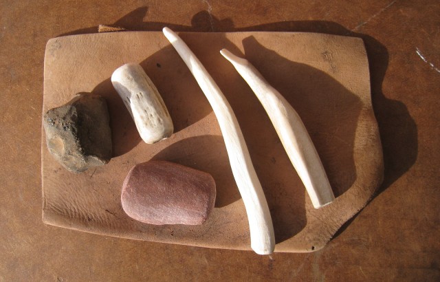 My flintknapping toolkit includes a billet, tine, hammerstone, and leather hide.