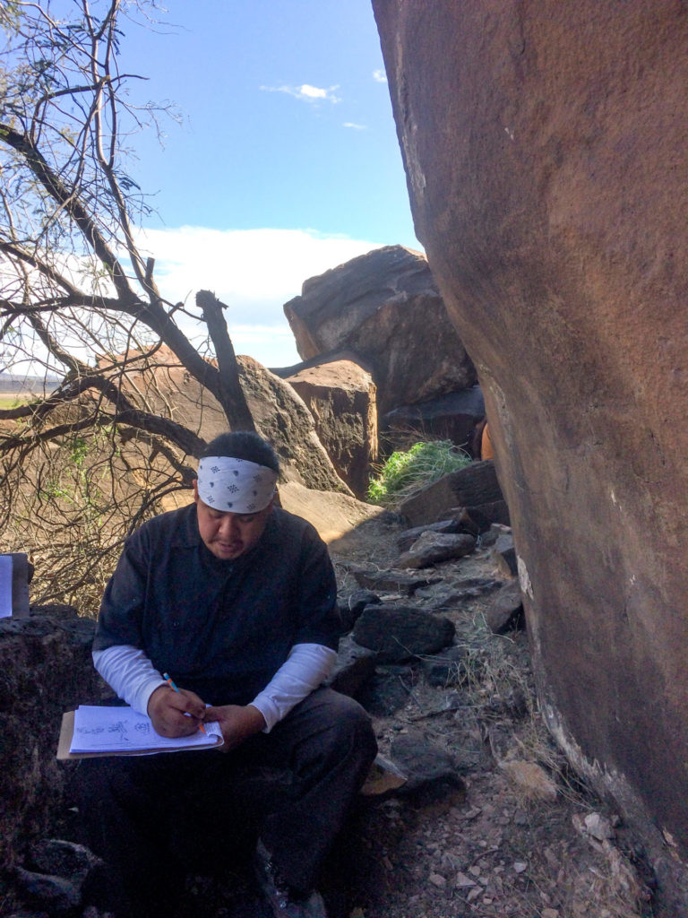 Charles taking detailed notes on a panel of petroglyphs.