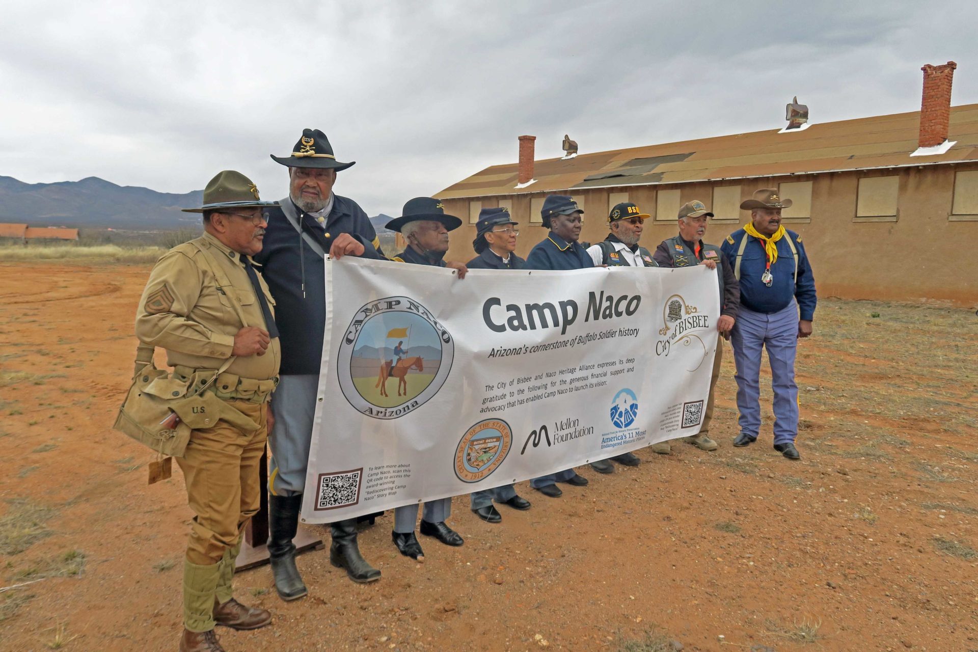 This image shows descendants and members of the Southwest Association of Buffalo Soldiers. The men and women are dressed in historical uniforms and holding a banner commemorating Camp Naco.