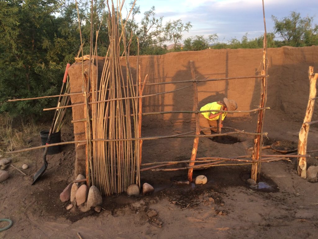 In this photo, Dee is mixing mud, and you can see the construction of the wattle-and-daub wall.