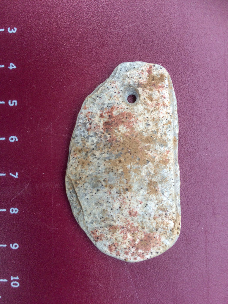 Painted ground schist pendant found along an Indigenous trail through the Maricopa Mountains (scale in centimeters).