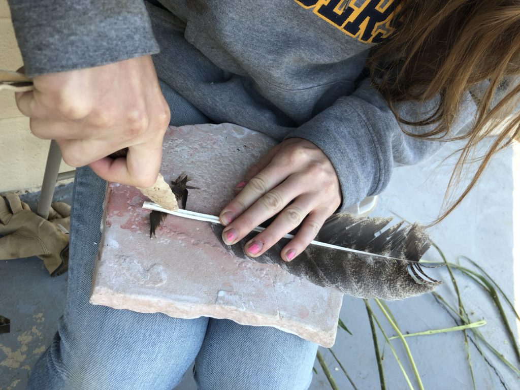 Using a stone knife to cut a feather for my atlatl dart. Image: Kristin Bridges