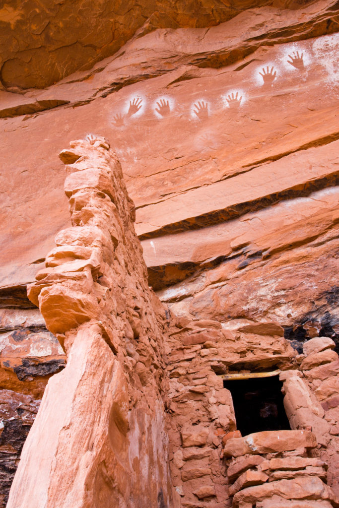 These negative handprints are displayed above an Ancestral Puebloan structure. © Jonathan Bailey