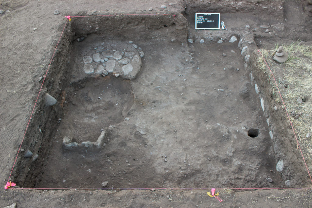 Unit overview. At left foreground is a slab-lined hearth. Above that is a probable cobble base for a granary. A historic-period pit has cut through both.
