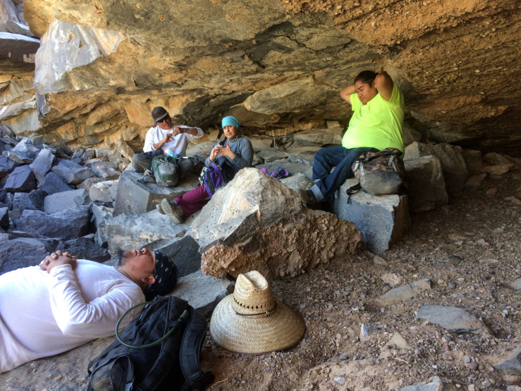 Field crew taking lunch in a shallow rock shelter (Keahna at center).