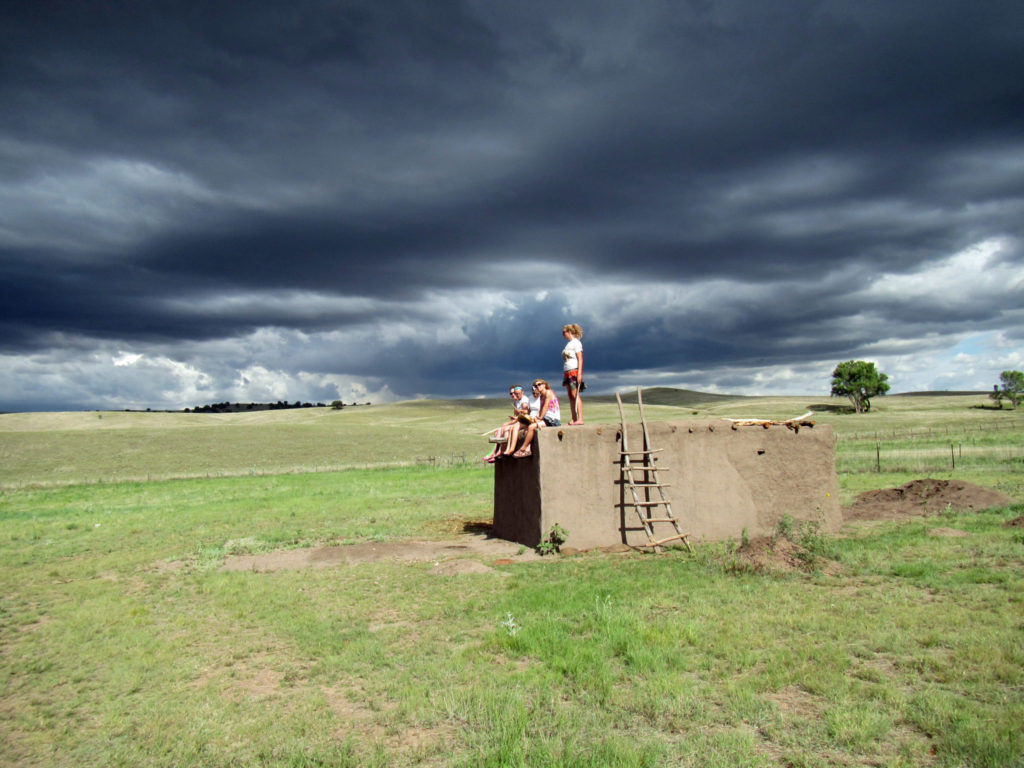 For me, this image captures the Preservation Archaeology conundrum and holds out the hope of a positive outcome. The threatening black clouds face off against powerful rays of sunshine. At the intersection, our field school students—the generation that must become the successful leaders in combatting climate change—gather atop the replica of an 800-year-old Pueblo room they built by hand to gain insights into the traces of the past they excavated nearby. The energy and optimism of these students, and their entire generation more broadly, lends some measure of hope. But time is of the essence, and all generations must step up.