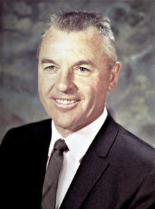 This is a photographic portrait of geologist and avocational archaeologist Raymond F. Robison, who worked in the Safford, Arizona, region. The protrait shows Ray's head and shoulders and faces slightly to his right (viewer's left). Ray has short gray hair, blue eyes, and is smiling. He wears a black sportcoat, white dress shirt, and dark gray necktie. He appears to be middle-aged, in his 50s.