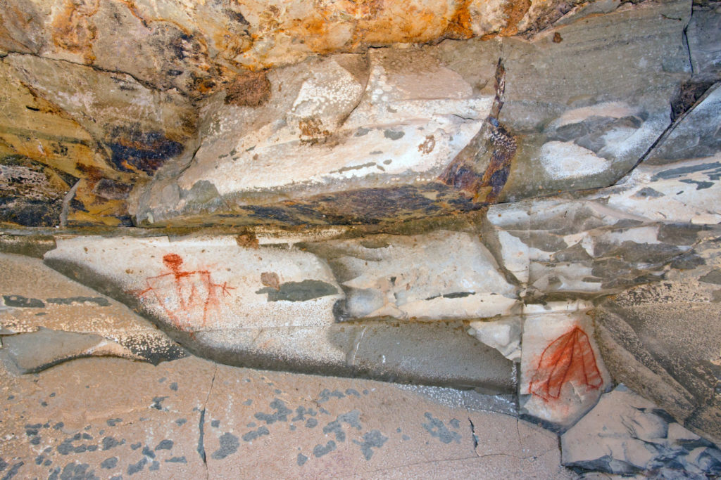 Fremont pictographs created with a crayon-like mineral block. The pictograph on the left displays an anthropomorphic (or human-like) character with spread arms. Image © Jonathan Bailey